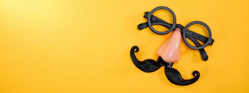 A fake mustache and glasses on a yellow background.