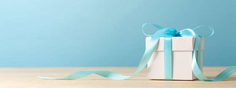 A white gift wrapped in light blue ribbon.