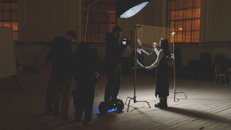 A performer on stage, looking through a mirror.