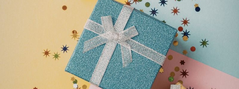 A glittery blue wrapped gift with confetti around it.