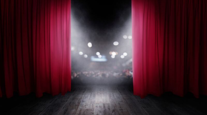 A curtain opening to a full audience.