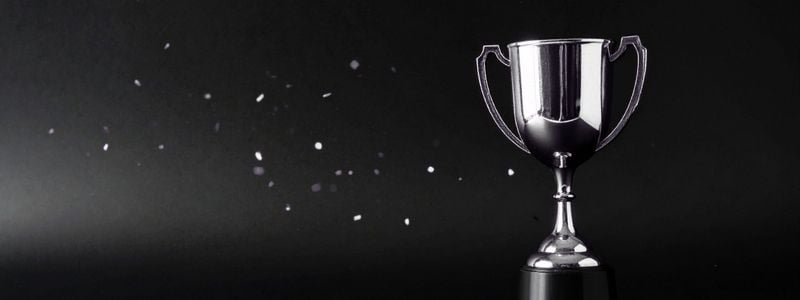 A silver award with confetti on a black background.