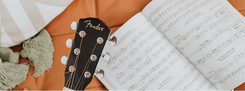 A guitar lying on some sheet music.