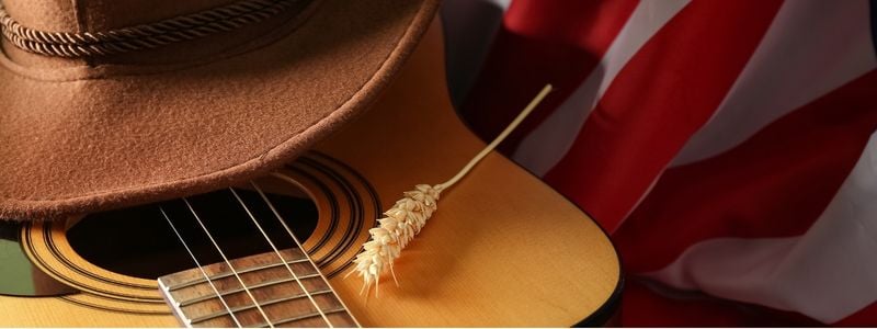 A cowboy hat on top of a guitar and a flag.
