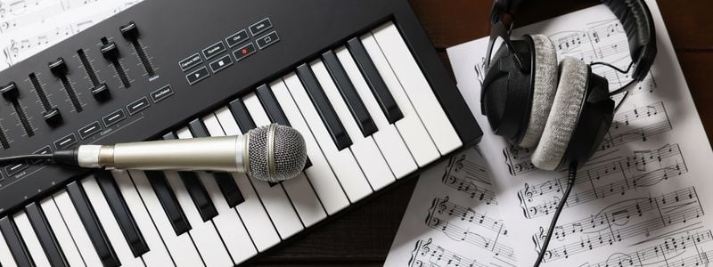 A keyboard, microphone, headphones, and some sheet music.