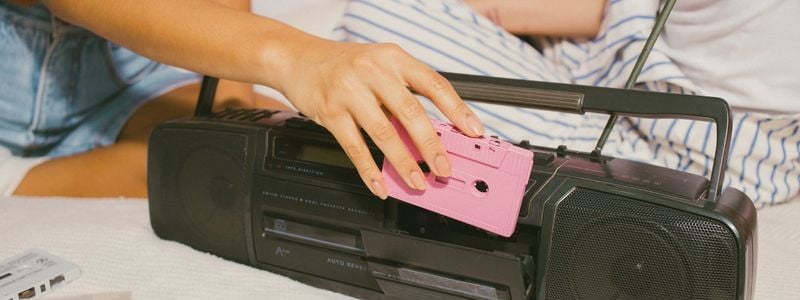 A pink cassette tape in front of a boom box.