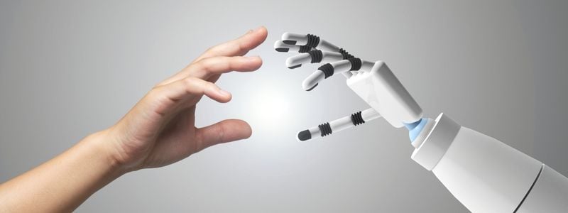 A human hand reaching for a robot hand.