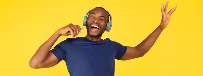 A singer with headphones and a yellow background.