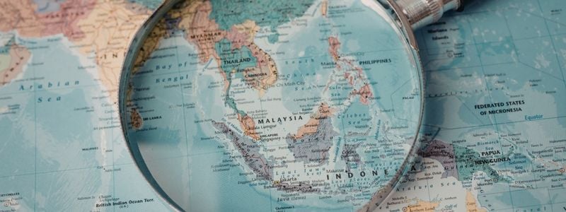 A magnifying glass on top of a map of Asia.