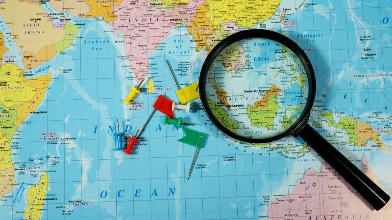 A magnifying glass on top of a map of Asia.