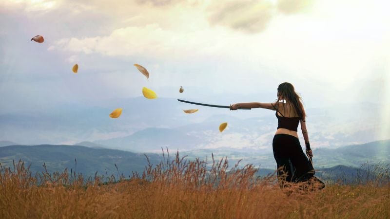 A woman on a hill causing leaves to move with her mind.