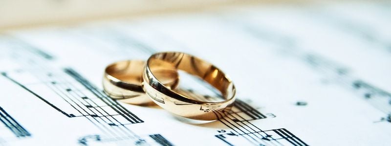 Two wedding rings resting on piano sheet music.