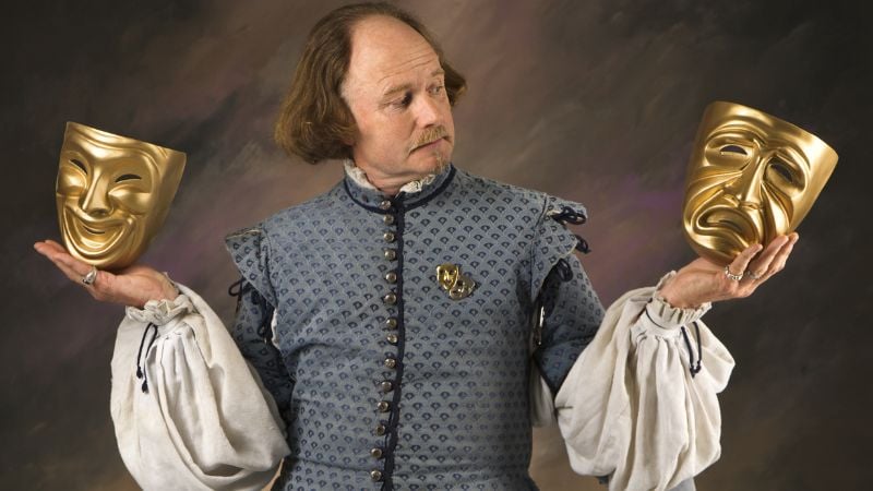 Shakespeare holding theatre masks.