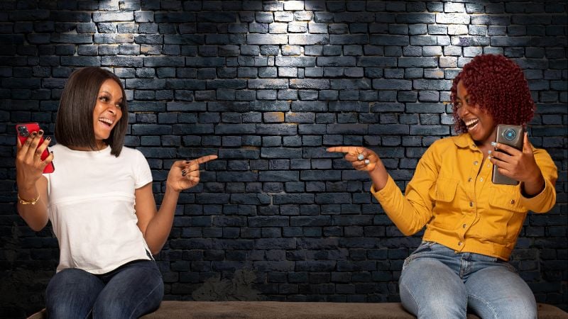 Two smiling friends pointing to each other on stage.