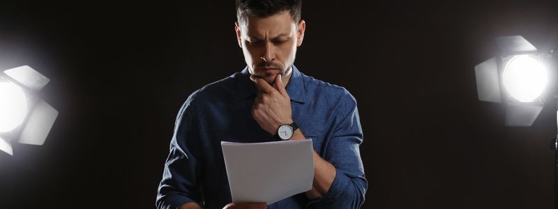 A man on stage studying a script.