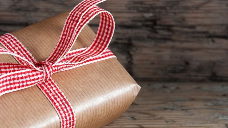 A gift on wooden boards, tied with red checkered ribbon.