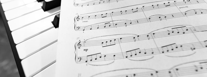 Piano keys with sheet music on top.