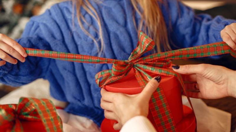 A mother and child tying a gift with a bow.