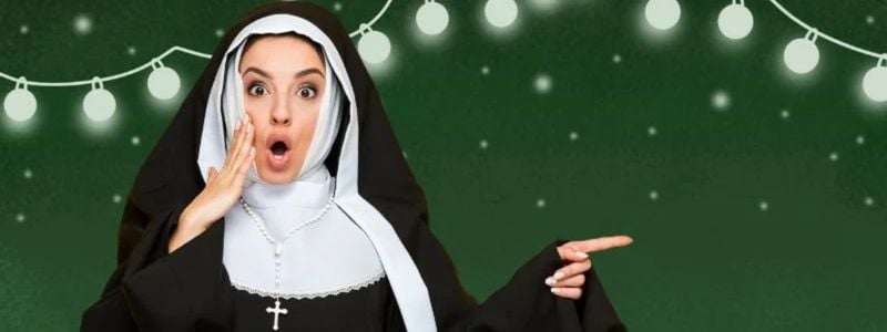 A surprised nun in front of festive lights.