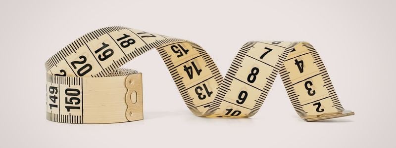 A flexible tape measure on a beige background.
