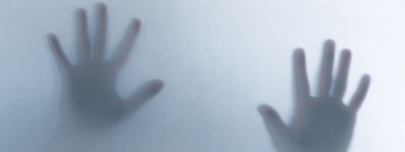Two hands pressed against frosty glass.