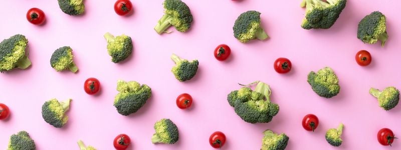 Broccoli and tomatoes on a pink background.