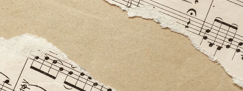 Torn vintage sheet music on a taupe background.